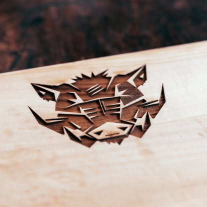 Tiefe Lasergravur eines geometrischen Wildschweinkopfs in Holz